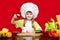 Happy little girl in chef uniform cuts vegetables in kitchen. Kid chef