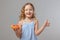 Happy little girl child holds half a grapefruit with a straw and shows thumb up. Healthy food. Gray background, studio