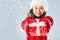 Happy little girl with Christmas gift on snow background