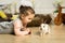 A happy little girl in a dress sits in a nest and holds a cute fluffy white Easter bunny