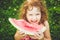 Happy little girl eating watermelon in summer park. Instagram filter.