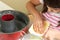 Happy little girl greasing a mold to bake a cake