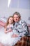 Happy little girl and her grandmother are sitting together and hugging in the bedroom. They are smilling and kissing. Maternal
