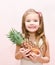 Happy little girl holding ripe whole pineapple