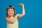 Happy little girl holds in hand a banana, like a dumbbell and shows biceps, concept of sport as a lifestyle