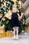 Happy little girl jumps beside christmas tree enjoying christmas