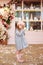 Happy little girl with long curly hair in a blue dress and beret stands in a street French vintage cafe. Childhood concept. French