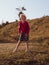 Happy little girl with long hair portrait jumping on nature background windy day. Cute kid walking alone in autumn park