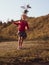 Happy little girl with long hair portrait jumping on nature background windy day. Cute kid walking alone in autumn park