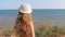 Happy little girl with long hair raising hands on a hill with sea view on windy day. Cute kid walking alone on beach. Pretty child