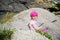 Happy little girl in pink sun hat on the rocks