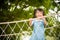 Happy little girl playing climbing on the rope bridge