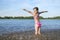 Happy little girl playing with water on the river bank, on a sunny day