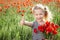 Happy little girl on poppy meadow giving thumb up