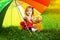 Happy little girl with a rainbow umbrella in park. Child playing