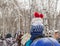 Happy little girl in a red hat with pompoms and a blue jacket with deer riding a pony in a winter Park, the pleasure of