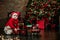 Happy little girl in a red sweater with a deer plays with Christmas gifts - a toy railroad. Family Christmas morning in a