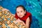 Happy little girl in a red vest swimming in the pool of the water park. Child learns to swim. teaching a child to swim