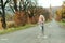 Happy little girl running on the road in autumn time. Stylish fashion child outdoors. Autumn holidays. Childhood, leisure and