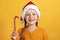 Happy little girl in santa hat with christmas candy. A child on a yellow background color