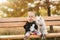 Happy little girl sit on the bech in the autumn park with her little white dog. Happy childhood. Autumn concept