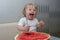 Happy little girl smiling and eating watermelon, holding a large spoon, vitamins, summer