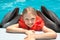 Happy Little Girl Smiling with two Dolphins in Swimming Pool