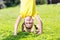 Happy little girl standing on her head on green lawn.