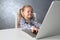 Happy little girl studying computer work. Child with white laptop.