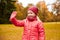 Happy little girl waving hand in autumn park