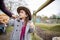 Happy little girl wearing cowboy hat interacts with her mom on a farm