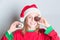 Happy little girl wearing santa claus hat holds Christmas donuts, smiling, having fun.