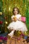 Happy little girl in white dress sit on chair christmas backgro