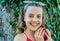 Happy little kid with beauty look smile with ripe red apple in summer garden, smiling