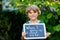 Happy little kid boy with chalk desk in hands. Healthy adorable child outdoors On desk When I grow up I want to be in