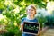 Happy little kid boy with chalk desk in hands. Healthy adorable child outdoors On desk - police officer - in German as