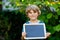 Happy little kid boy with chalk desk in hands. Healthy adorable child outdoors Empty desk for copyspace holding by