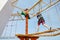 Happy little kid boy climbing on high rope course trail. Active child making adventure and action on family vacations