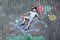 Happy little kid boy having fun with bicycle and air balloons picture drawing with colorful chalks on ground. Children