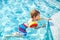 Happy little kid boy having fun in an swimming pool. Active happy child learning to swim. with safe floaties or swimmies