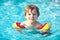 Happy little kid boy having fun in an swimming pool. Active happy preschool child learning to swim. with safe floaties