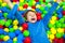 Happy little kid boy playing at colorful plastic balls playground high view. Funny child having fun indoors.