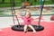 Happy little kid girl having fun on a swing on playground. Active kid play on school or kindergarten yard. Healthy