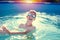 Happy little kid in goggles enjoying summer in swimming pool