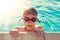 Happy little kid in goggles holding edge of swimming pool