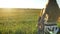 Happy little kid running to young mother and embracing her, beautiful wheat or rye field during sunset in background