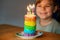Happy little preschool girl celebrating birthday. Closeup of child with homemade rainbow cake, indoor. Happy healthy