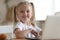 Happy little preschool kid sitting at table with computer.