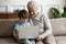 Happy little schoolboy using computer with senior old grandfather.