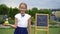 Happy little schoolgirl with a chalkboard outdoor